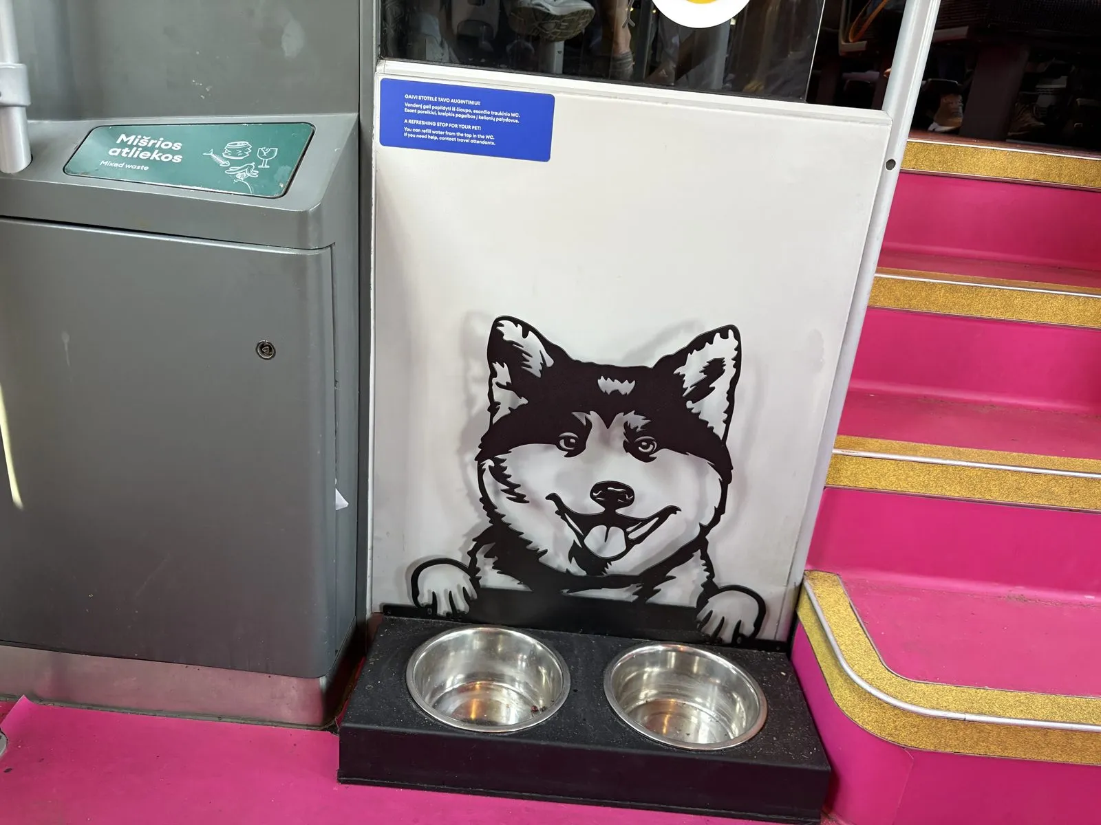 ピンク色に装飾された列車の車内。犬のイラストの横に水飲み用の器が置かれている