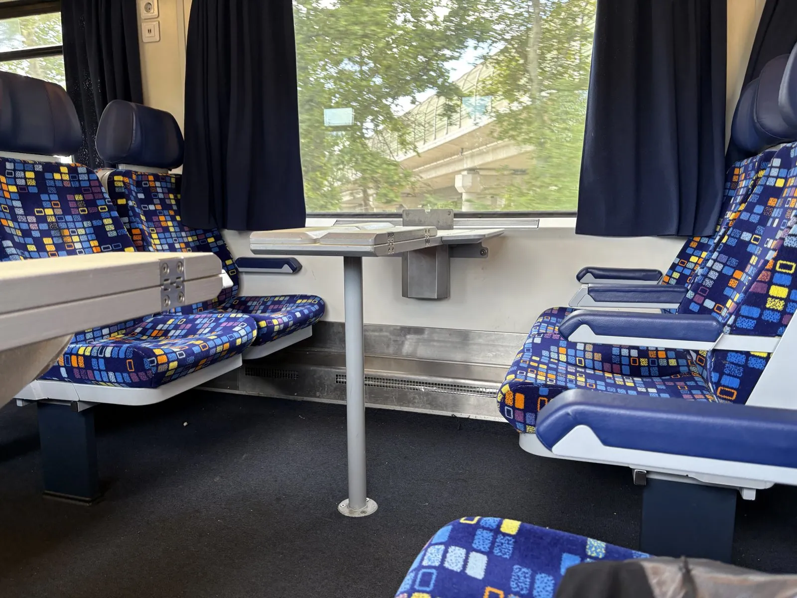 帰りの列車の車内。青地にカラフルな四角模様の座席と、窓際の小さなテーブル